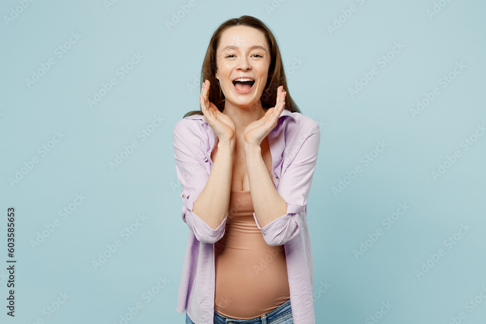 Fototapeta premium Young fun pregnant future mom woman with belly tummy with baby wear casual clothes scream sharing hot news with hands near mouth isolated on plain pastel blue background. Maternity pregnancy concept.