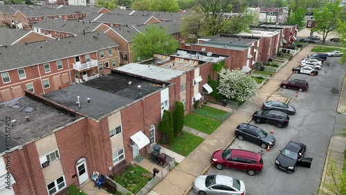 Close up aerial of low income housing in urban city during spring. Cars parked outside of houses with cop cruiser. Poverty and dangerous neighborhood theme.