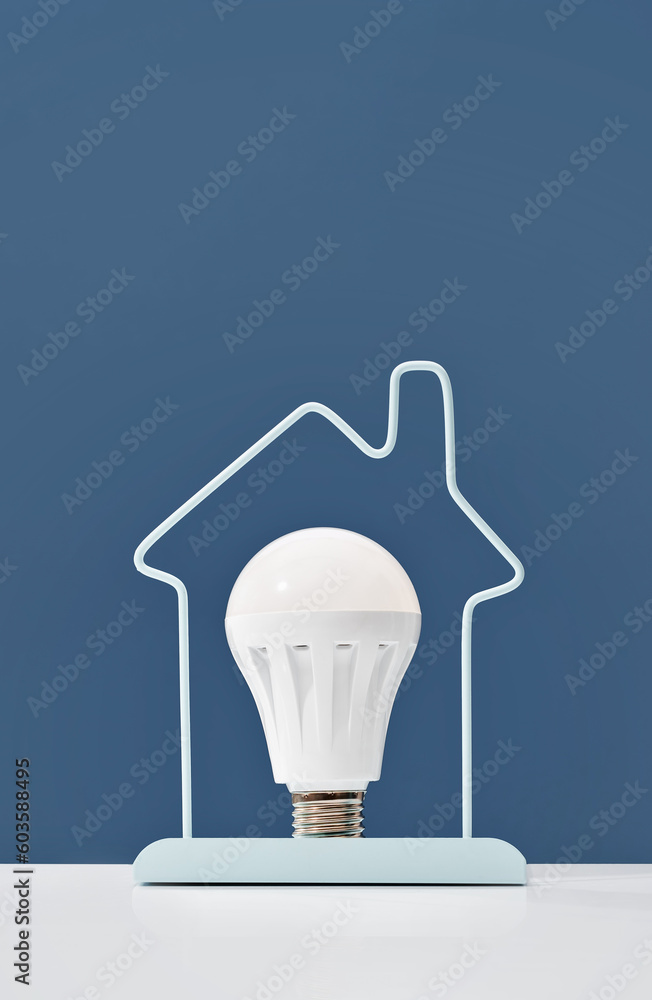 Glowing LED light bulb inside house frame on blue background. Green ...