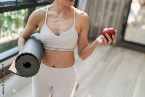 Fitness woman holding yoga mat with Fresh Apple Heathy clean vegan food before working out in yoga studio