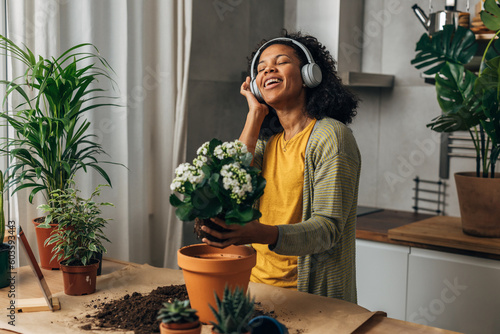 A beautiful Multiracial woman enjoys working with plants. She listens to music and sings.