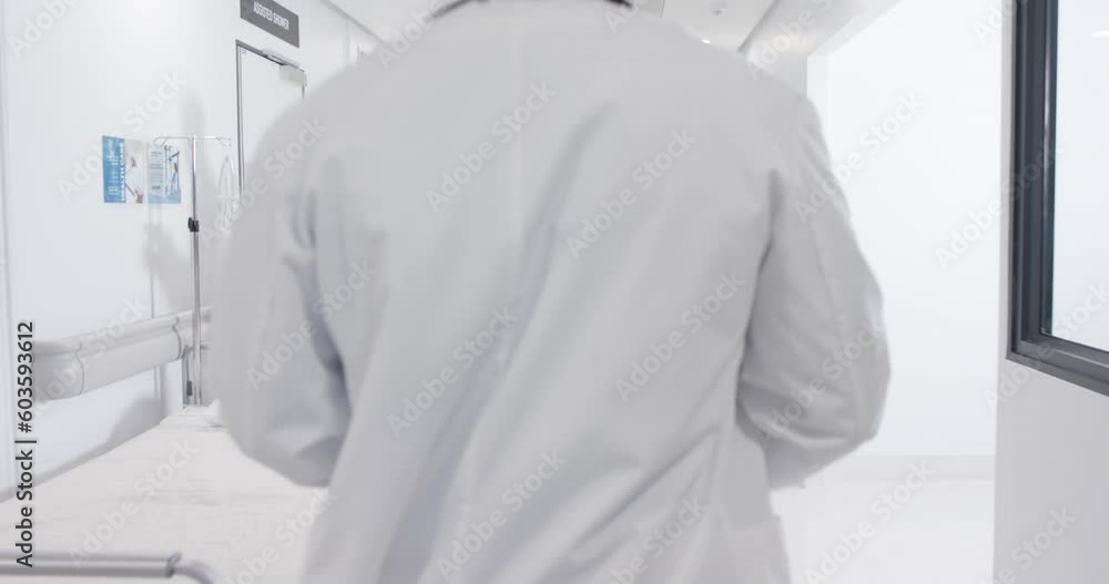 Serious diverse male doctors talking and female nurse with wheelchair in slow motion, unaltered Serious diverse male doctors talking and female nurse with wheelchair in slow motion, unaltered