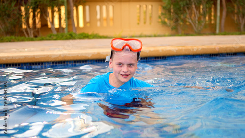 A little boy in a swimming masck has fun in the outdoor pool photo