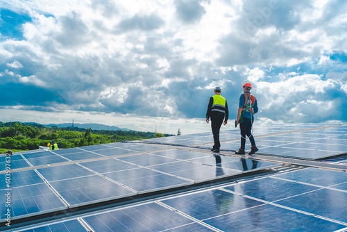 Technician engineer service meeting and checking solar cell on rooftop of industrial factory. Inspection worker repair solar cell panels. Clean Renewable energy, Ecology and alternative power concept