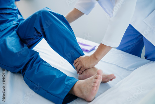 Physiotherapist Helping Patient While Stretching His Leg in bed in clinic .