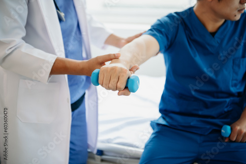Asian physiotherapist helping male patient stretching arm during exercise correct with dumbbell in hand during training hand  in hospital © laddawan