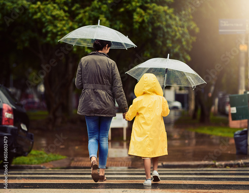 Vászonkép Back, raincoat or umbrella with a mother and daughter walking across a street in the city during winter