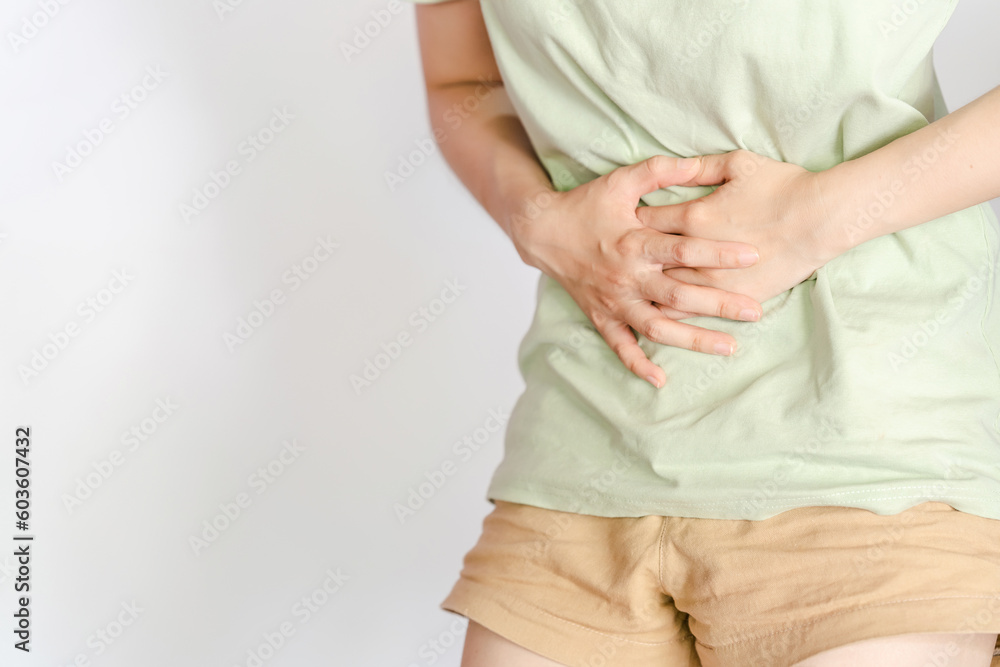 A woman in a green shirt shows abdominal pain that can be caused by gastritis, intestinal disease, cystitis or menstruation. A woman in a green shirt shows abdominal pain that can be caused by gastritis, intestinal disease, cystitis or menstruation.