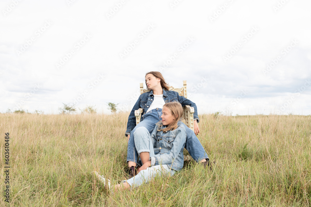 Girl friends sitting in grassy field Girl friends sitting in grassy field