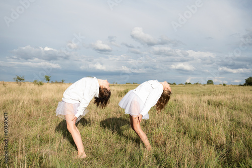 Smiling girl friends doing ballet pose in field