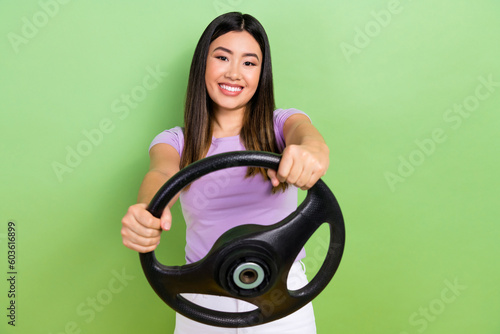 Full length size photo of young cheerful japanese girl hold steering wheel enjoy soft driving road isolated on green color background