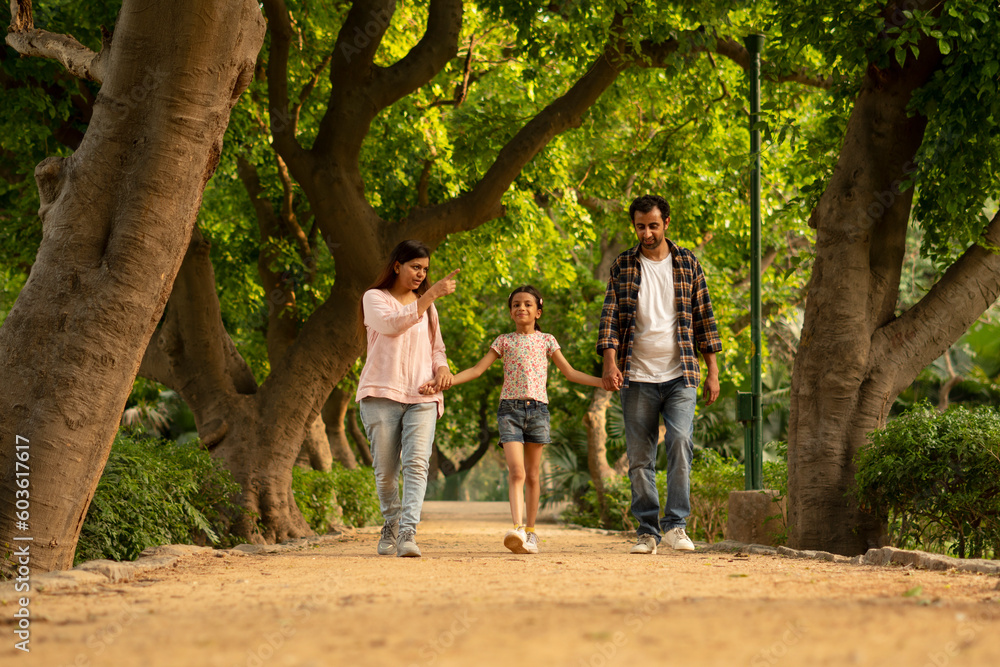 Fototapeta premium couple walking in the park with daughter