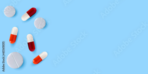 White pills and red-and-white pills on a blue background. The concept of treatment and recovery. A health design element for apps, websites and social networks. Medicinal pills.