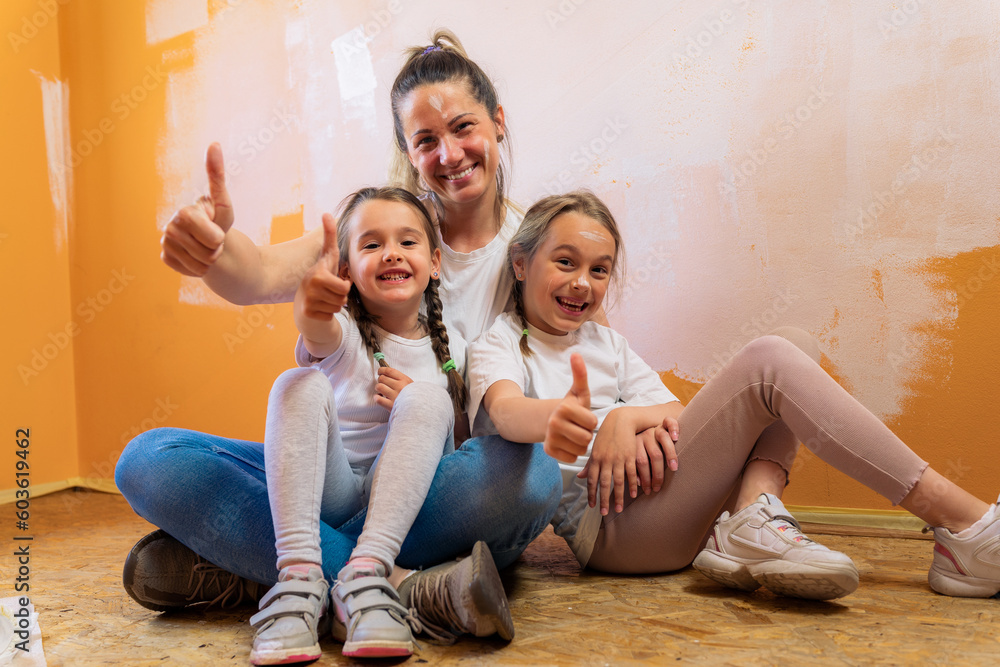 A mother hugs her daughters as they sit on the floor of the room they are renovating A mother hugs her daughters as they sit on the floor of the room they are renovating