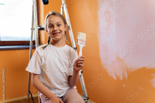 a young girl smeared with paint poses with a brush in her hand