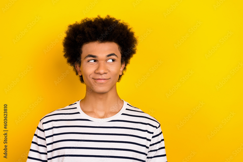 Photo of youngster guy dude look interested side cunning face wear striped white black t-shirt isolated yellow color background Photo of youngster guy dude look interested side cunning face wear striped white black t-shirt isolated yellow color background