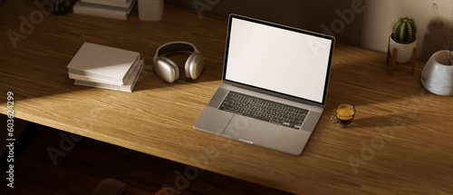 Workspace with laptop mockup, headphones, coffee cup, books and decor on a wooden table