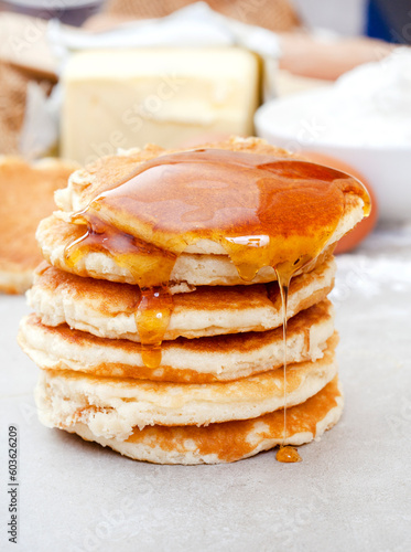 Fresh Pancakes stacked on kitchen table with syrup dripping down