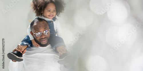 Happy multiracial family having fun at home together. Portrait of cheerful little biracial daughter riding on multiethnic father's neck smiling. Diverse ethnic dad laughing with his kid. Copy space.