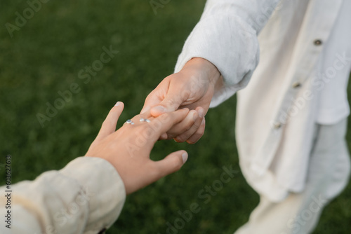 partial view of yoga man in white linen clothes holding hand of young woman outdoors © LIGHTFIELD STUDIOS