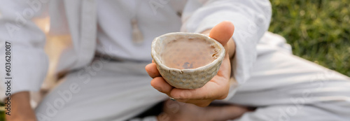 Canvas Print cropped view of blurred man holding ceramic bowl with tea outdoors, banner