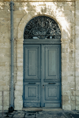 Old-fashioned gray wooden front door with transom window in natural stone doorway   © Olga