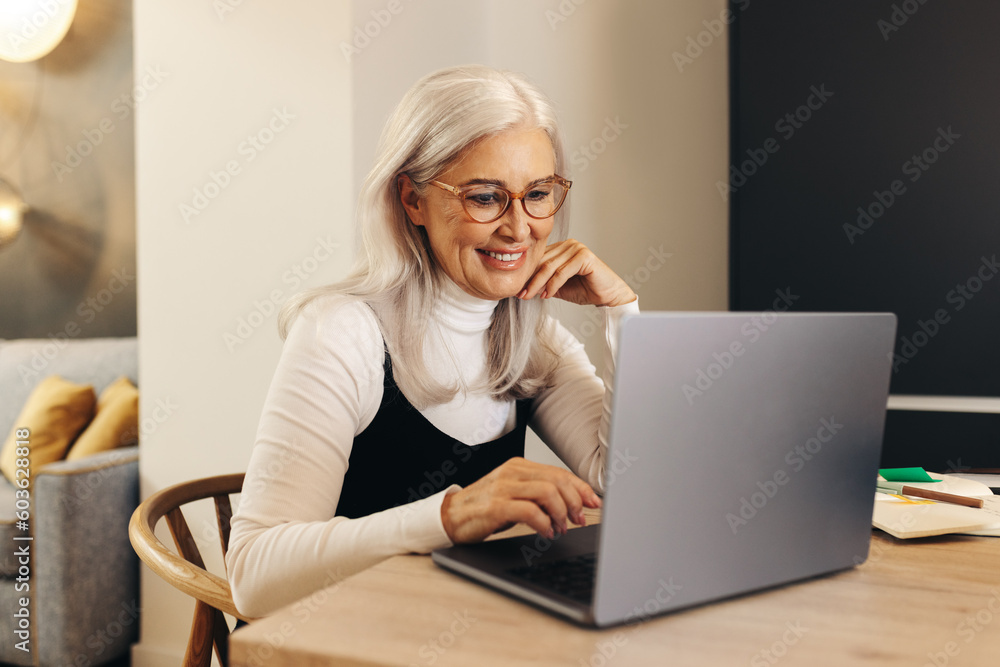 Happy senior woman working with a laptop in her home office Happy senior woman working with a laptop in her home office