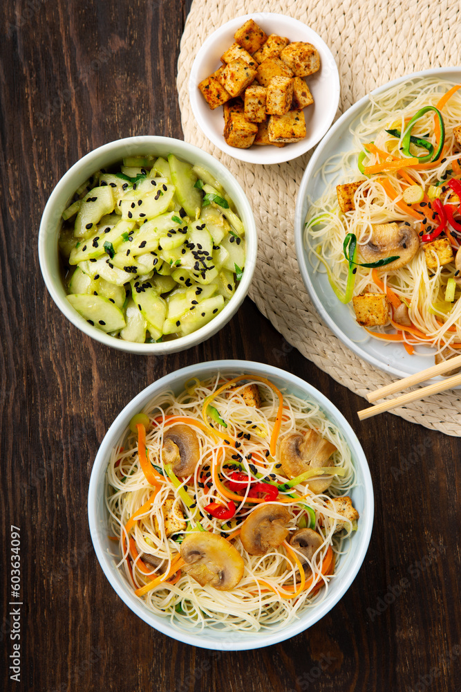 Vegan Rice Noodles with Tofu, Peppers, Carrots on Dark Brown Background Vegan Rice Noodles with Tofu, Peppers, Carrots on Dark Brown Background