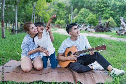Image of young Asian family playing together at park