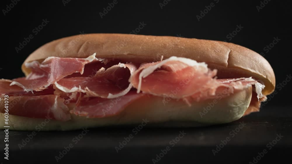 sandwich with sliced spanish iberico ham on black wooden board