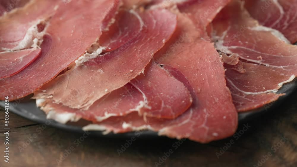 plate of sliced spanish iberico ham on wooden table background, rotating plate of sliced spanish iberico ham on wooden table background, rotating
