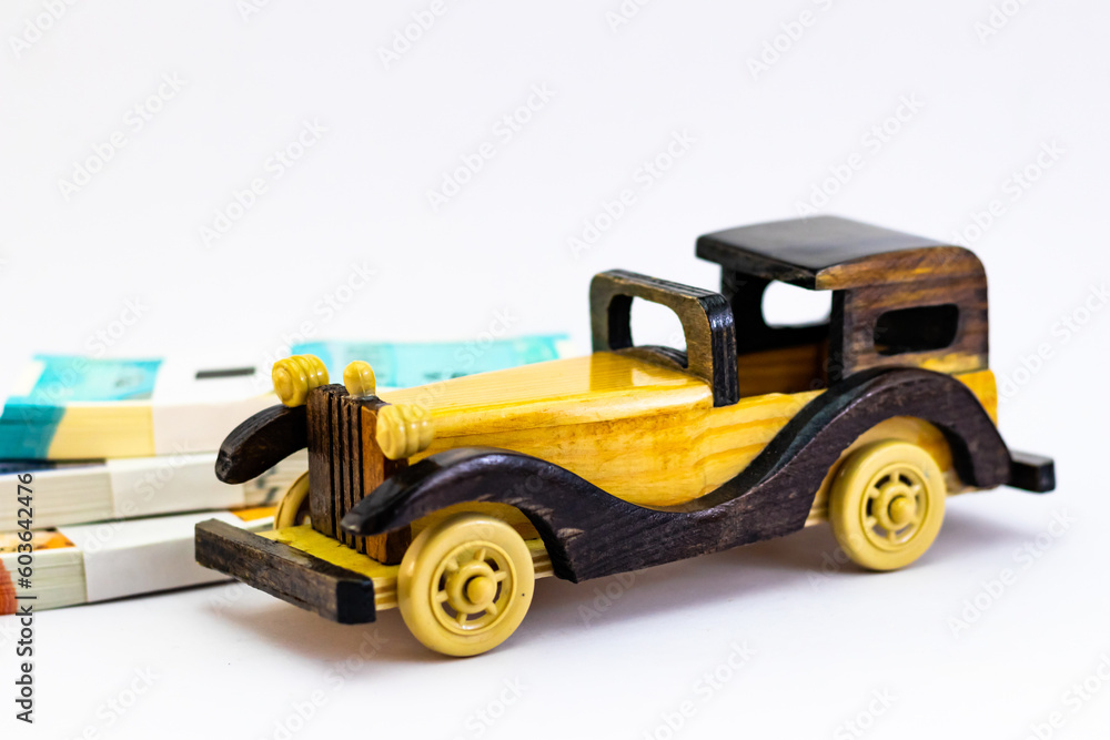 High angle shot of a woodne vintage car toy and monye bundles on white background.