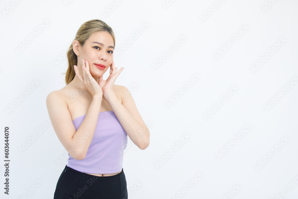 Portrait isolated cutout studio shot of Asian beautiful pretty cheerful female model in tube cropped top shirt standing smiling using hands massaging cream oil moisturizer on face on white background Portrait isolated cutout studio shot of Asian beautiful pretty cheerful female model in tube cropped top shirt standing smiling using hands massaging cream oil moisturizer on face on white background