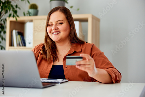 Canvas Print A content curvy woman checking her bank account over a laptop, indoors