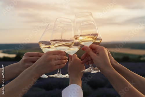 Obraz na płótnie A group of people clinking with wine glasses in front of a lavender field and amazing summer sunset. w salonie