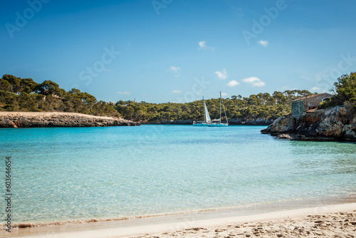 Cala S'Amarador beach with white sand and turquoise sea in natural parkland Cala Mondrago bay at Mallorca, Balearic islands, Spain. Sailboats floating on water