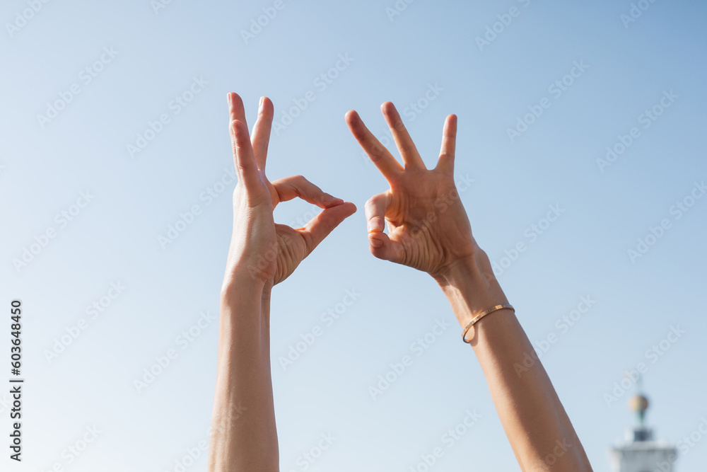 Cropped view of woman showing okay gesture with sky at background Cropped view of woman showing okay gesture with sky at background
