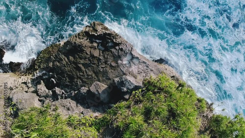Magnifficent top down view of sea tides crashing into rock cliff. Amazing tropical nature with azure sea waves, lots of foam and rocks with trees. Demonstartion of natural powers. Concept of travel. photo
