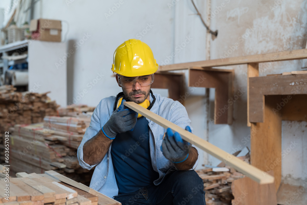 Male carpenter working in wood workshop. Male joiner wearing safety uniform, gloves, helmet and working in furniture workshop Male carpenter working in wood workshop. Male joiner wearing safety uniform, gloves, helmet and working in furniture workshop