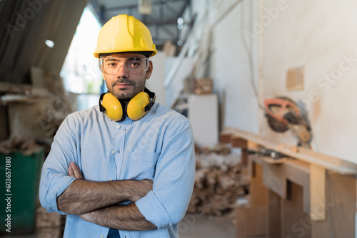 Portrait of male carpenter standing with arms crossed in the wood workshop. Man carpenter working at wood workshop. Young man carpenter at furniture workshop