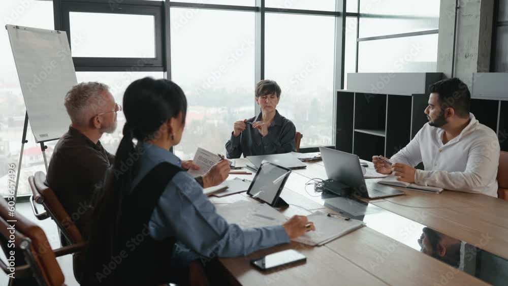 Concentrated multiethnic team of colleagues gathered around table and discussing project in office Concentrated multiethnic team of colleagues gathered around table and discussing project in office
