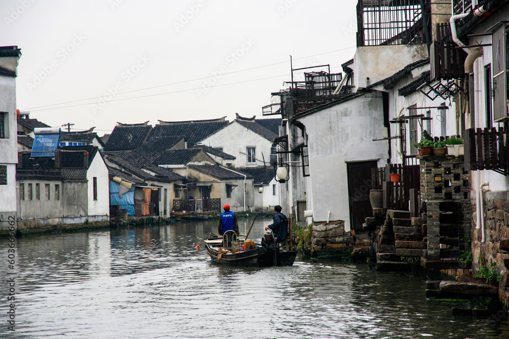 boat with two people travelling down a canal in suzhou