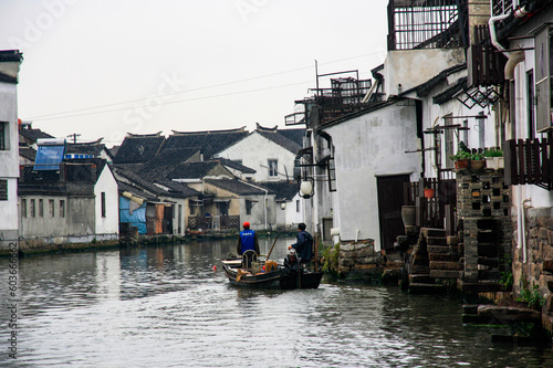 boat with two people travelling down a canal in suzhou