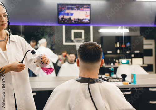 A barber does hair styling for a man in a barbershop. Men's professional hair salon. Barbershop