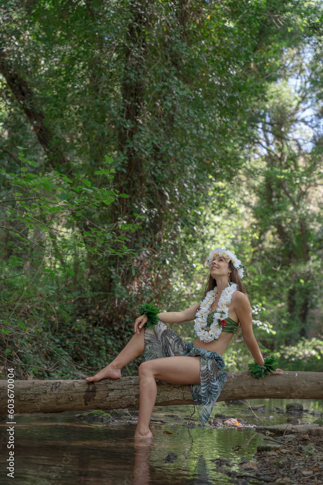 Hula dancer takes a break on a log in the middle of the river in a beautiful green landscape full of nature. Hula dancer takes a break on a log in the middle of the river in a beautiful green landscape full of nature.