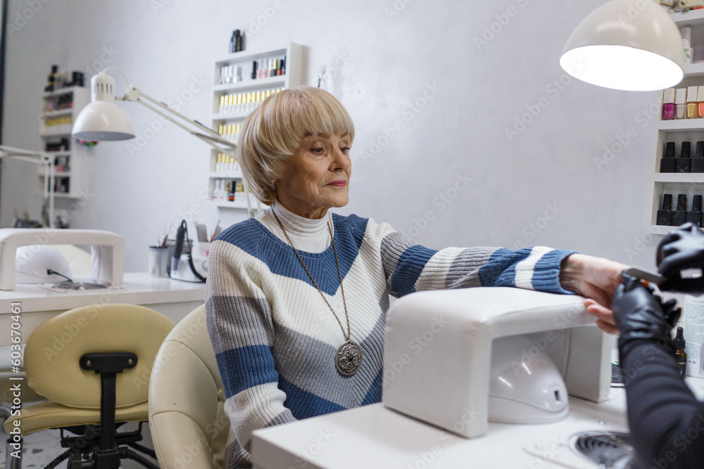 An elderly woman does a professional manicure in a beauty salon An elderly woman does a professional manicure in a beauty salon