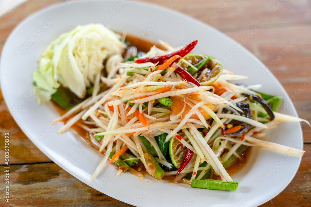 Spicy Thai food green papaya salad or Som Tum with salted crab on white dish. Asian food Thai style.