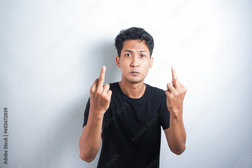 Young handsome Asian man wearing black tshirt giving middle finger Young handsome Asian man wearing black tshirt giving middle finger