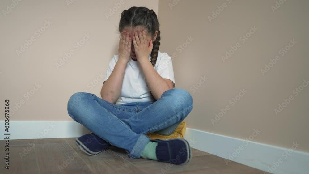 Sad little child is sitting on floor in room. girl covering her face with her hands is crying in corner. Child abuse at home. Punishment of child at home. girl is sitting sad in corner of room. Sad little child is sitting on floor in room. girl covering her face with her hands is crying in corner. Child abuse at home. Punishment of child at home. girl is sitting sad in corner of room.