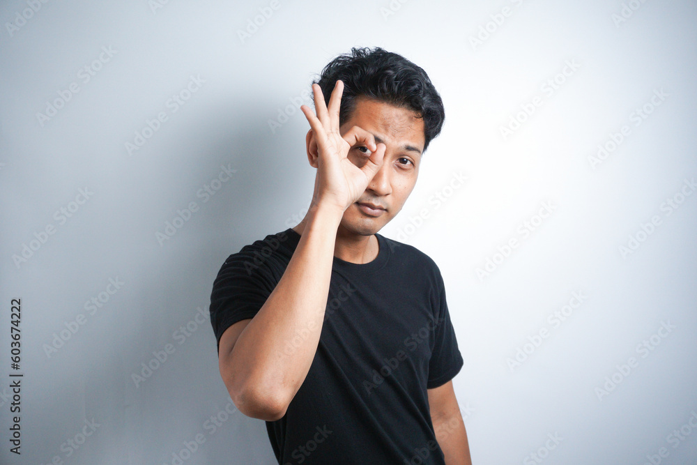 Asian handsome man over isolated background showing ok sign with fingers Asian handsome man over isolated background showing ok sign with fingers